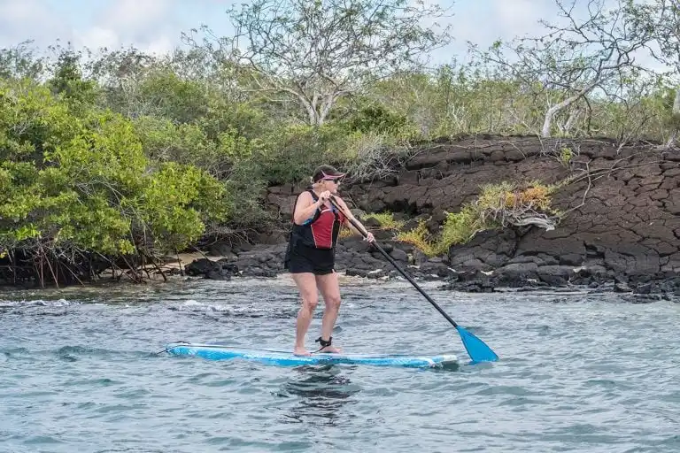 Guest from Yacht La Pinta paddleboarding in the serene waters of the Galapagos Islands, Ecuador.