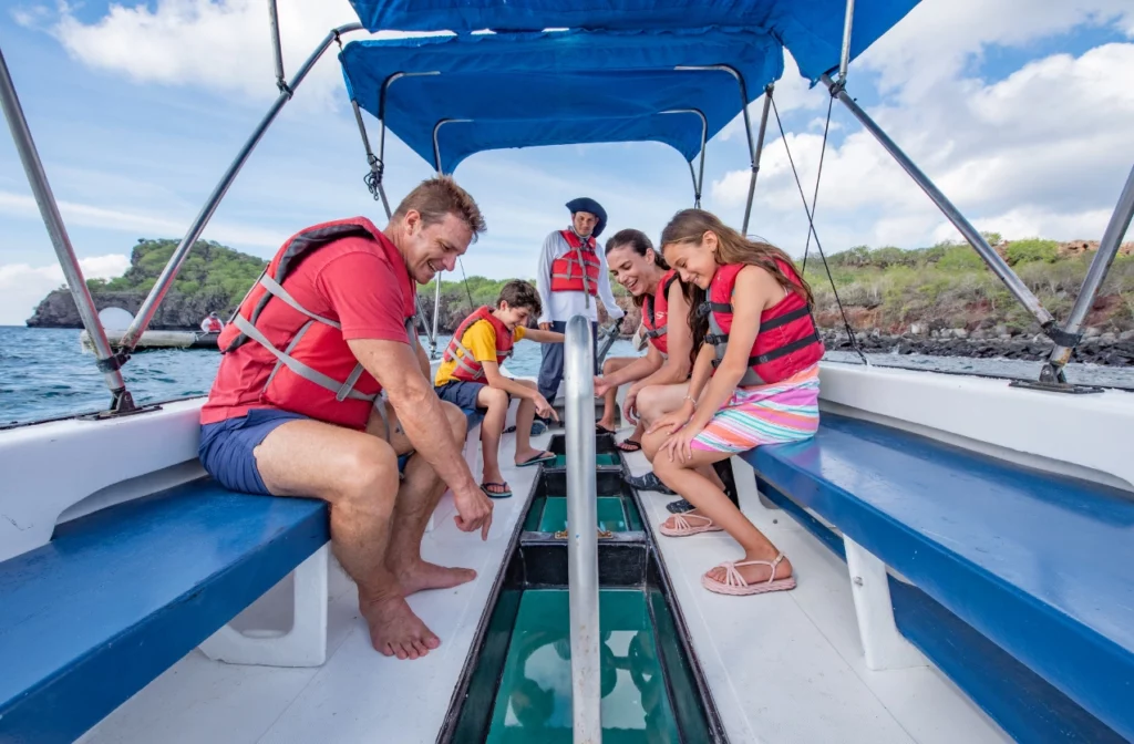 Family looking through the glass bottom of a boat to observe marine life in the Galapagos Islands.