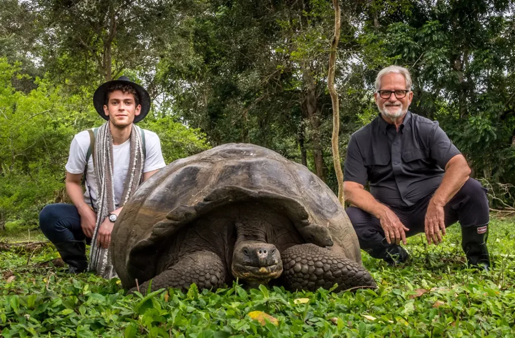 Two guests posing with a giant tortoise in the Santa Cruz highlands