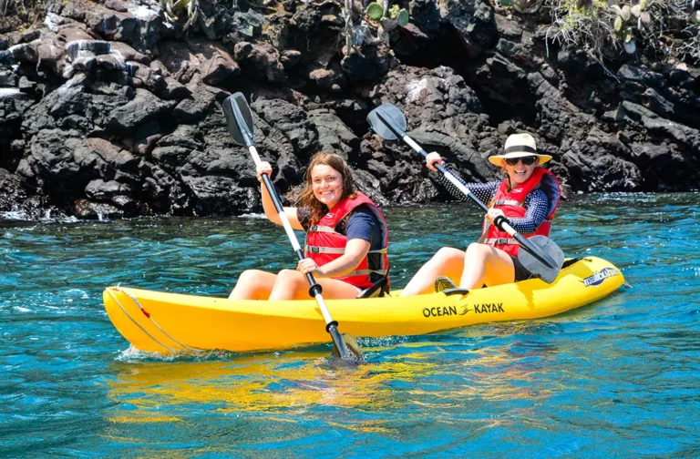 Two guests kayaking along the volcanic coastline near Dragon Hill, Santa Cruz Island