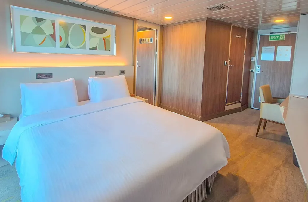 Spacious cabin aboard Yacht La Pinta featuring a king bed with white linens, warm wood paneling and a private seating area.