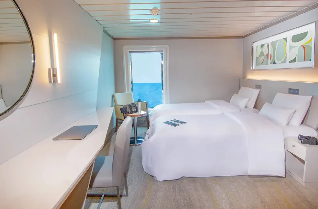 Bright and modern double cabin aboard Yacht La Pinta with a large ocean view window, white bedding and minimalist decor.