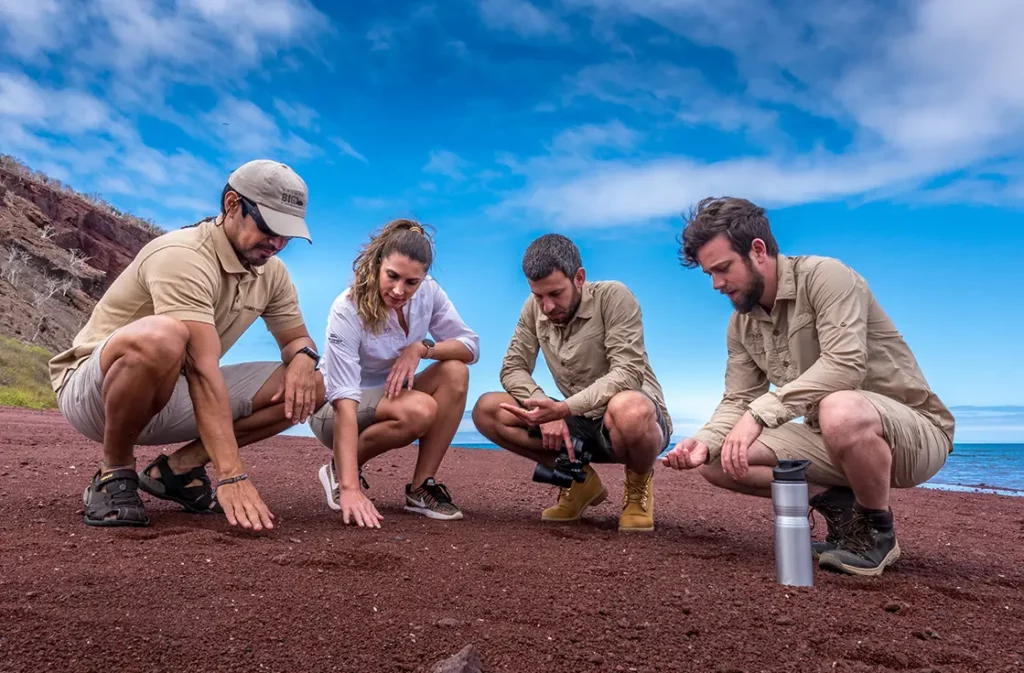Guests exploring the red sand beach of Rabida Island in the Galapagos
